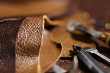 Pieces of natural cow leather and working tools in the tailoring workshop. Close-up.