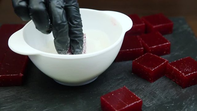 confectioner hand rolls crimson marmalade piece in sugar
