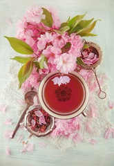 vintage, antique cup of fruit tea decorated with cherry flowers on white background in a shabby chic look