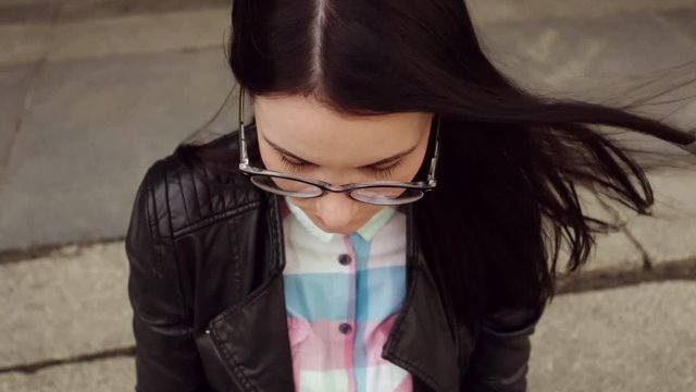 The girl's face with glasses, dark hair, close-up in slow motion.