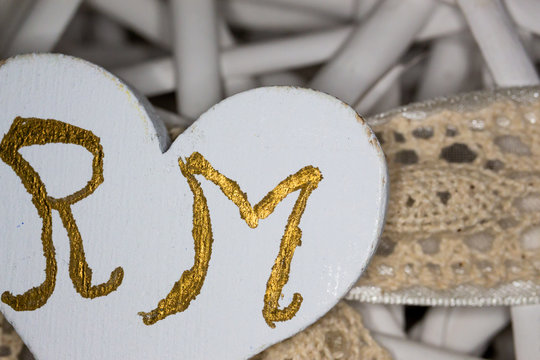 Homemade decorations for the wedding. The initials of the colored grooms of gold, on a wicker basket in the shape of a heart where to put dragees.