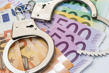 Euro banknotes with handcuffs on white background