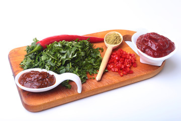 Fresh green cilantro, coriander leaves, tomato paste, chili pepper and spices on a wooden board. Ingredients for meat sauce.