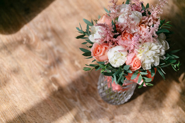 Wedding bouquet of white peony and pink roses wooden table. Lots of greenery, modern asymmetrical disheveled bridal bunch