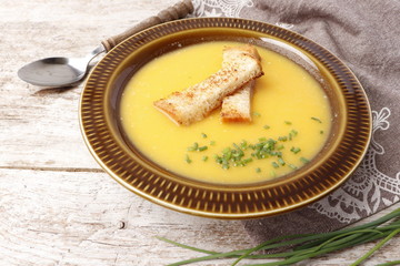 Pumpkin soup puree in a bowl with bread crumbs and chopped chives onions.