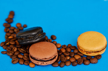 three chocolate macaroni with sticks of cinnamon and coffee beans on a blue background