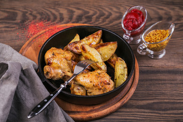 Fried chicken legs with fried potatoes in pan