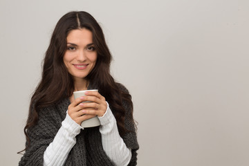 Portrait of brunette in gray cardigan. Having cup of coffee. Isolated on white background. Mid age...