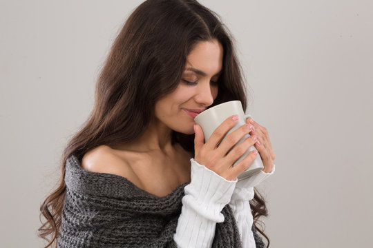 Side view iamge of brunette woman having cup of coffee. Wearing gray cardigan. Mid age woman over 35 years old beauty concept.