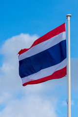 national flag of Thailand blowing in the wind with blue sky in background