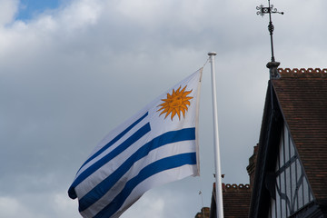 Fototapeta premium close up of national flag of Uruguay blowing in the wind with blue sky in background