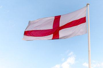 Fototapeta na wymiar national flag of England St Georges flag blowing in the wind with blue sky in background