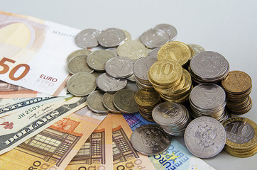 Stacks of Ruble coins on Euro Dollar Ruble banknotes on solid color background