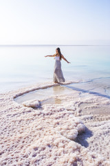 Blonde young girl in a long skirt on the shore of the dead sea. Jordan