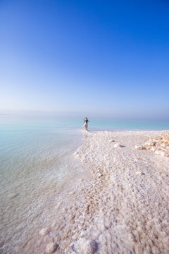 Blonde young  woman in a long skirt on the shore of the dead sea. Jordan