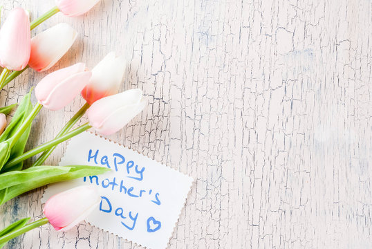 Mother's Day concept, greeting card background. Flowers tulips and greeting note Happy Mother's Day on a light concrete table, copy space top view