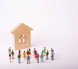 A crowd of people standing and looking at a wooden house on a white background. Buying and selling of real estate, rent. Affordable housing. A group of tourists visiting the sights. Selective focus