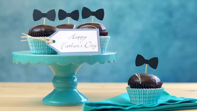 Happy Father's Day close up of woman setting up chocolate cupcakes on cake stand on table.