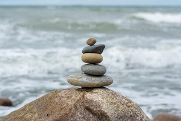 Fototapeta na wymiar Stacked Stones on top of a huge stone in the ocean