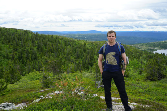 View mountains and a tourist standing on a footpath.