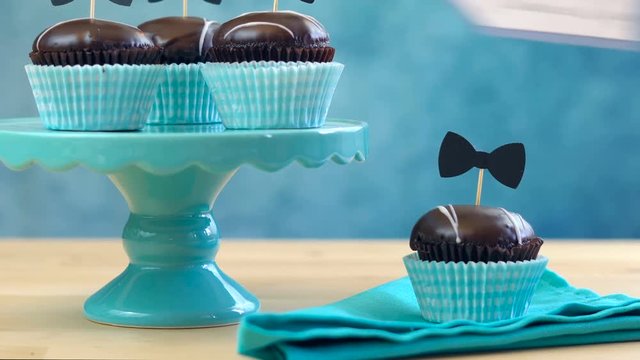Happy Father's Day close up of woman setting up chocolate cupcakes on cake stand on table.
