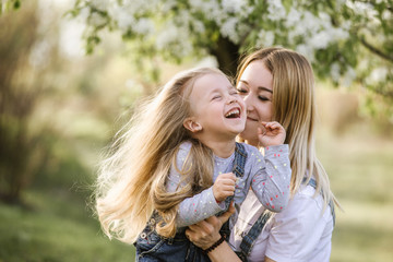Fototapeta premium young mother with adorable daughter in park with blossom tree