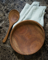 Empty wood bowl with wood spoon on brown granite. 