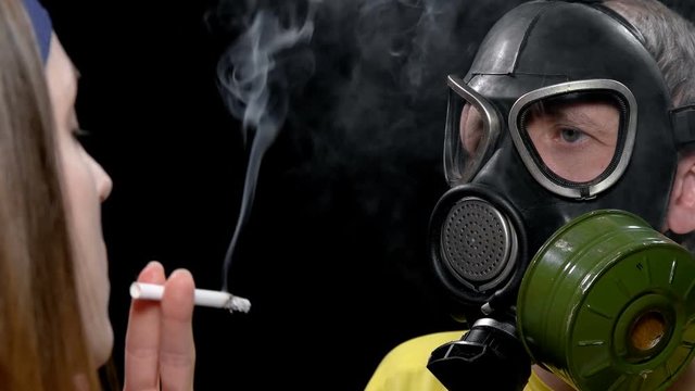 young man in gas mask to protect cigarette Smoking friend from harm,  close-up