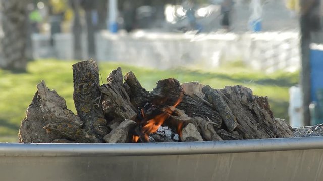 Wooden logs in a barbecue burning in a bonfire or campfire at sunset