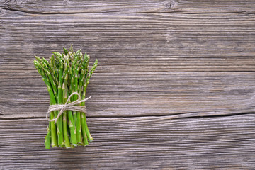 Organic food. Bunch of asparagus on rustic wooden background. Top view, copy space.