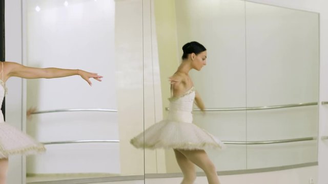 Young beautiful ballerina dressed in white tutu dancing gracefully on her pointe ballet shoes. 4K