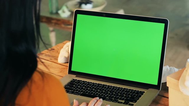 closeup view of woman hands using notebook typing on laptop keyboard with blank green screen copy space for advertising content text mockup chromakey wooden table business lady internet searching