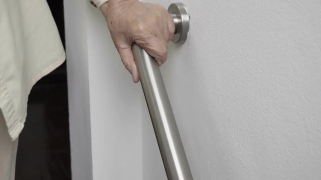 Elderly woman holding on handrail for safety walk steps