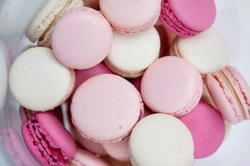 Pink white crimson macaroons lie in a transparent vase