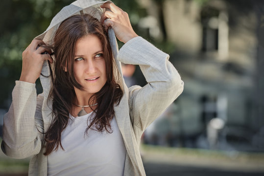 Pretty young woman in hood having walk in the city