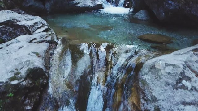 natural waterfall in the mountains, aerial view with drone following river
