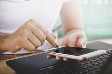 woman hand using smart phone and computer laptop for her work, technology with people concept 