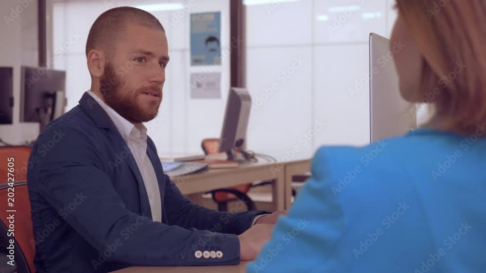 Poster young business man has meeting with unrecognizable woman. bank worker sitting at the workspace using computer talking with client