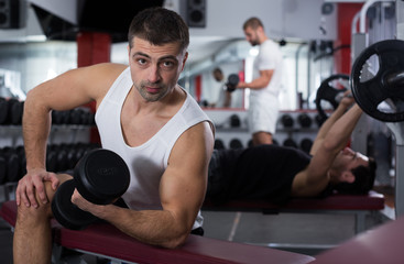 Guy during workout in gym with dumbbells