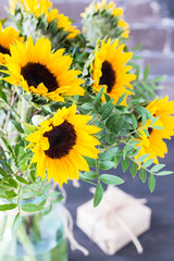 Bouquet of bright sunflowers in a glass jar on a wooden table.