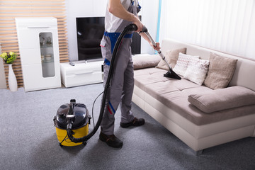 Person Cleaning Sofa With Vacuum Cleaner