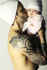 Bel homme musclé et tatoué embrassant son bébé 