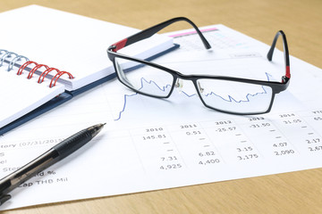 pen, notebook, glasses and financial report