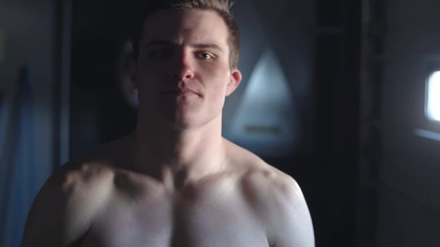 Camera tilts up across the shirtless torso of a young attractive male MMA fighter looking straight at the camera in slow motion MOODY SETTING