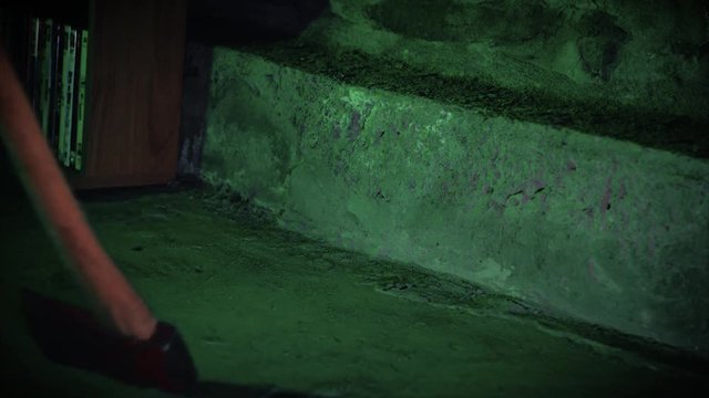 Close-up of an axe being grabbed and dragged across a dirty concrete floor.