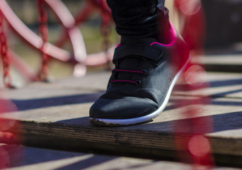 child's foot in a sneaker on a wooden bridge