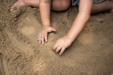 Hands of child playing with sand outdoor