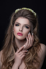 portrait of a girl close-up with nice hair style, manicure and make-up. The crown of flowers adorns her head