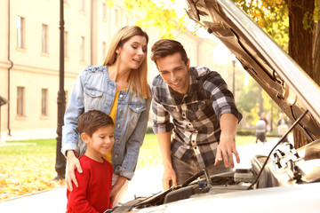 Young family repairing car, outdoors