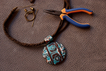 Assembly of boho pendant with pliers and decor elements. Handmade jewelry from polymer clay.
